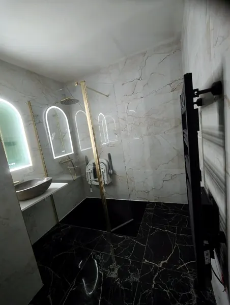 Salle de bain en marbre noir avec miroirs en arche lumineux, posée par Yoann Micallef