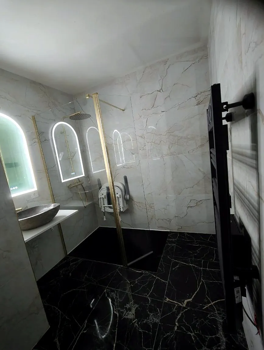 Salle de bain en marbre noir avec miroirs en arche lumineux, posée par Yoann Micallef